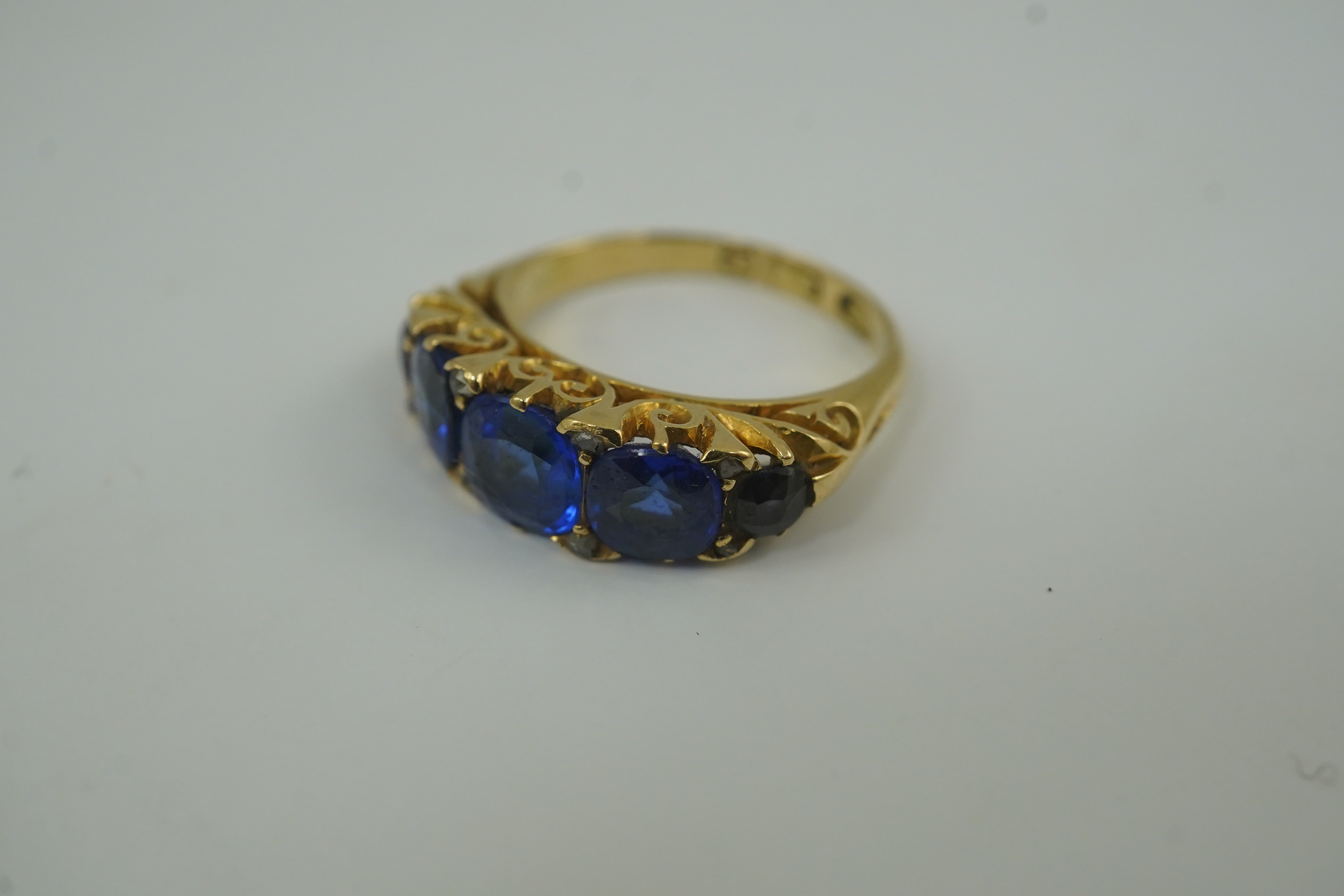 A late Victorian 18ct gold and graduated five stone blue doublet set half hoop ring